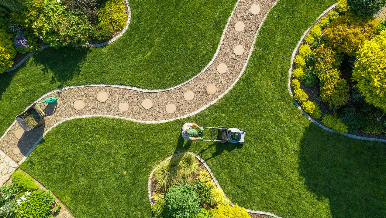 A man using an equipment to cut the lawn and maintain the grass short.